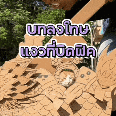 a cat is sitting in a cardboard sculpture with a purple and white sticker that says ' uaa '