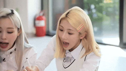 two blonde girls are sitting at a table eating food .