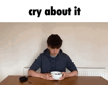 a boy is sitting at a table holding a bowl of cereal and crying .