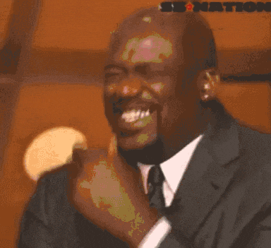 michael jordan is wearing a suit and tie and is making a funny face .