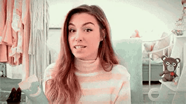 a woman in a pink and white striped sweater is sitting in a chair in a room .