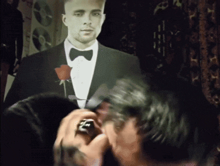 a man in a tuxedo with a bow tie holds a rose in his hand