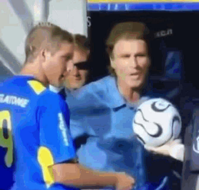 a man in a blue shirt with the number 9 on it holds a soccer ball