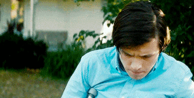 a man in a blue shirt is sweating while standing in front of a white house .
