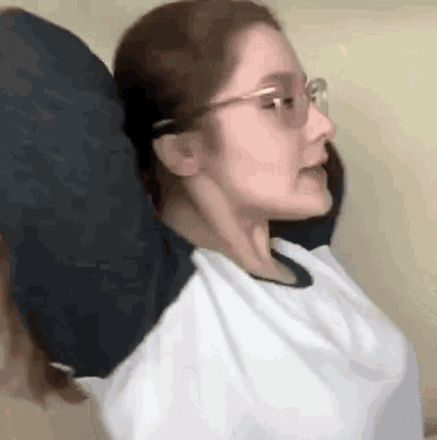 a woman wearing glasses and a white shirt is stretching her arms out .
