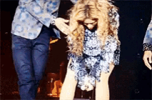 a woman in a blue dress is being helped up by two men on a stage