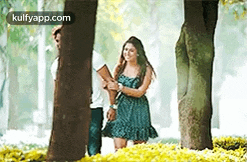 a woman in a green dress is standing next to a man in a white shirt in a park .