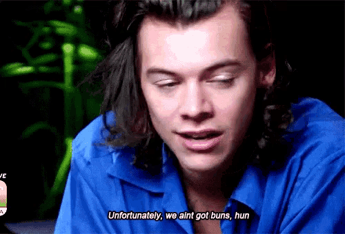 a man with long hair is wearing a blue shirt and says unfortunately we ain t got buns , hun .