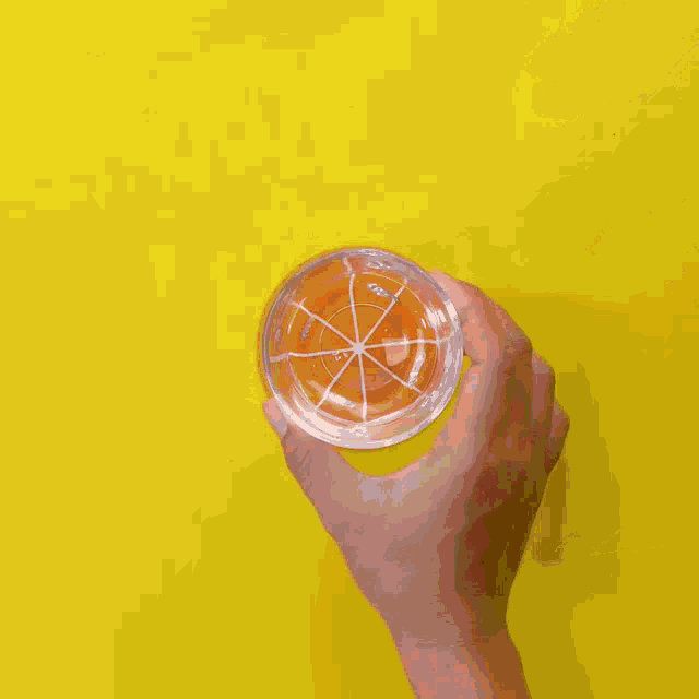 liquid is being poured into a glass on a yellow background