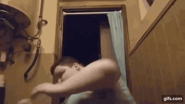 a man is standing in a bathroom with a towel on his head .
