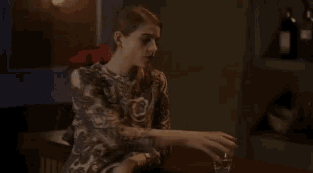 a woman in a paisley dress is drinking from a glass .