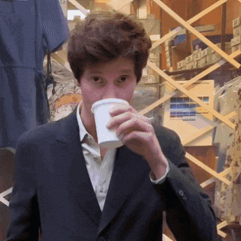 a man in a suit is drinking from a cup in a store