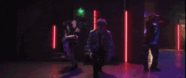 two men are dancing in a dark room with neon lights .