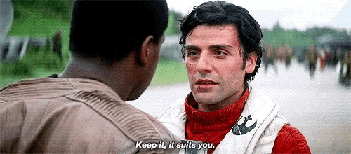two men are standing next to each other on a street and one of them is talking to the other .