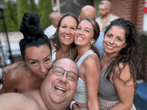 a group of people posing for a picture including a man wearing glasses