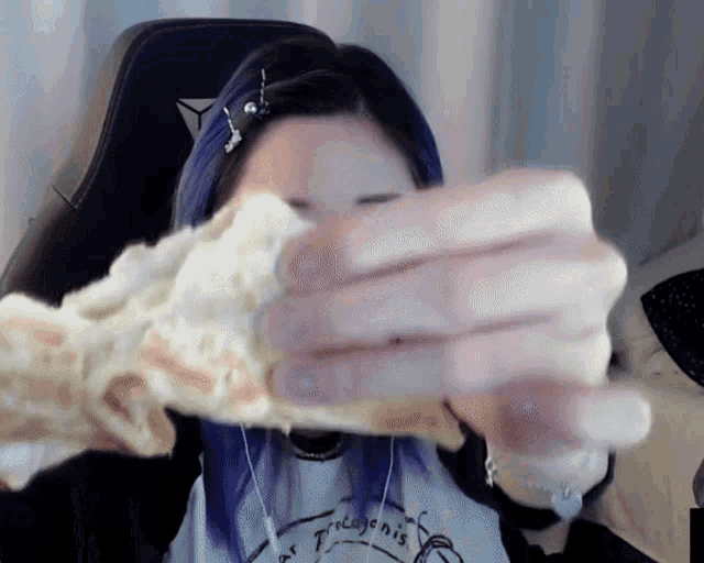 a woman with purple hair is holding a piece of bread in her hand
