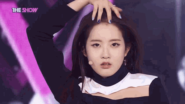 a woman with blue nails is holding her hair in front of a microphone while wearing a black and white top .