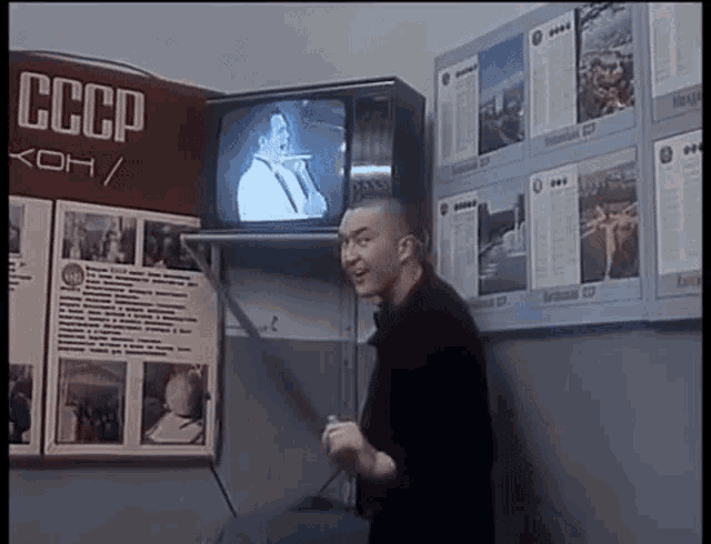 a man is standing in front of a cccp sign and a television