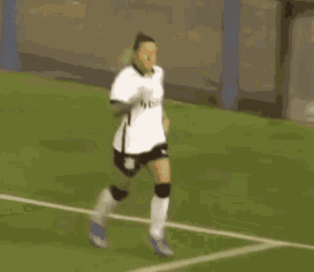 a woman is standing on a soccer field holding a soccer ball .