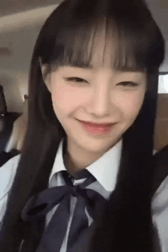 the girl is wearing a school uniform and tie and smiling .