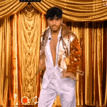 a man in a gold jacket is dancing in front of a gold curtain ..