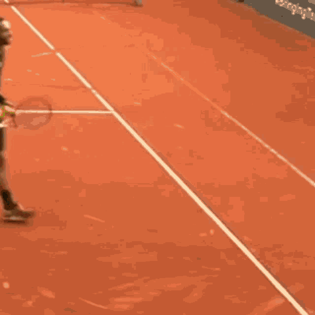 a man is walking on a tennis court holding a tennis racket .