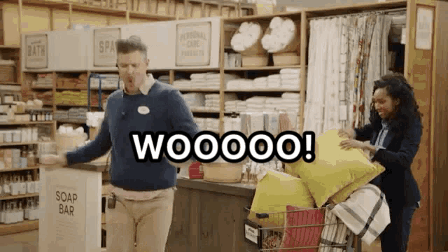 a man in a blue sweater is standing in a store with a sign that says soap bar