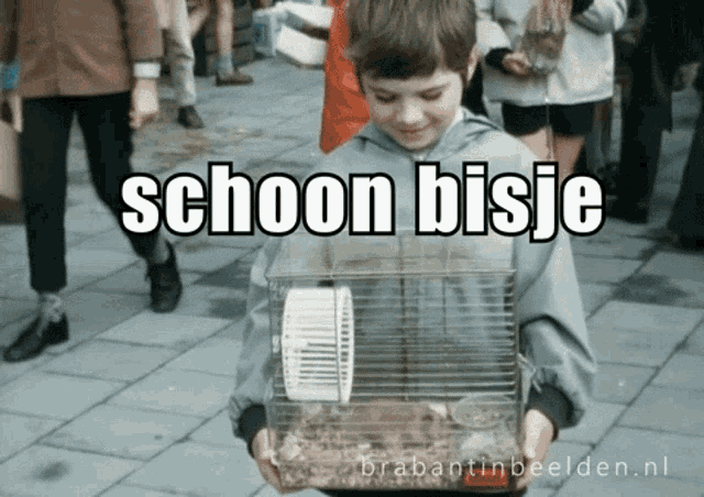 a young boy is holding a hamster cage with the words schoon bisje written on it