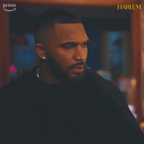a man with a beard is standing in front of a poster for harlem