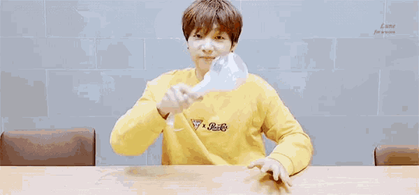 a young man in a yellow guess shirt holds a light stick