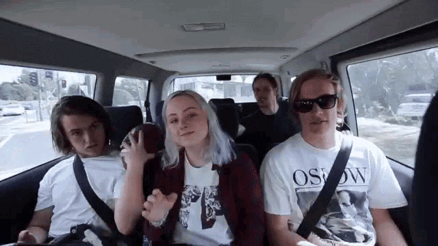 a group of people are sitting in the back seat of a van and one of them is wearing an osrow shirt