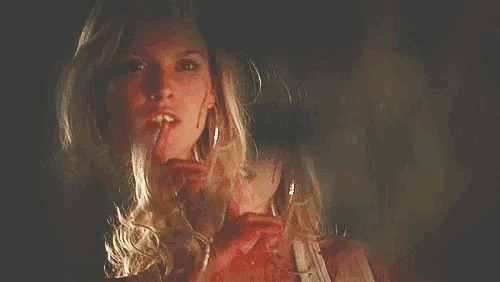 a woman with blood on her face is holding a glass of wine in her hand .
