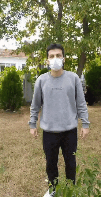 a man wearing a face mask and a grey sweatshirt with the word derrimo embroidered on it