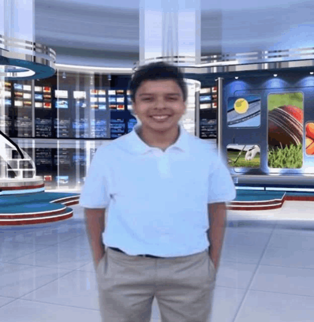 a boy in a white shirt and khaki pants stands with his hands in his pockets in a newsroom