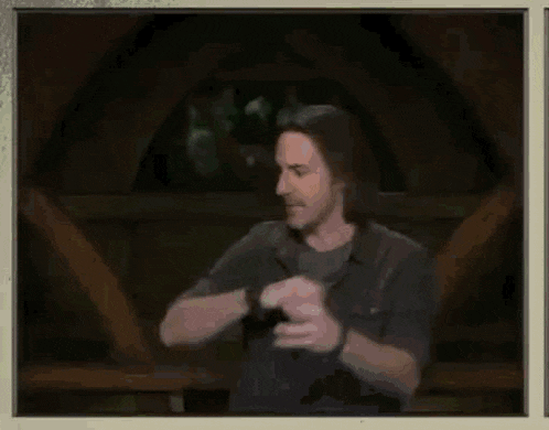 a man with long hair is wearing a watch and looking at his watch .