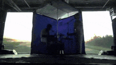 a man singing into a microphone in front of a blue curtain