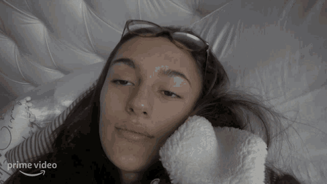 a woman wearing sunglasses is laying on a bed with an arrow pointing to the right that reads prime video