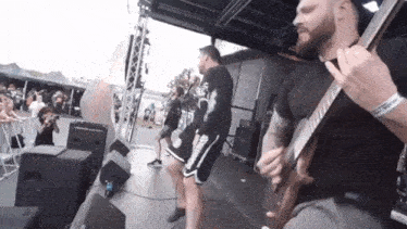 a man is playing a guitar on stage while another man stands behind him