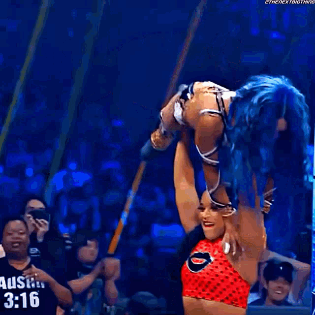 a woman in a red top is holding another woman in a wrestling match in front of a sign that says kodz