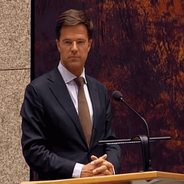 a man in a suit and tie stands at a podium