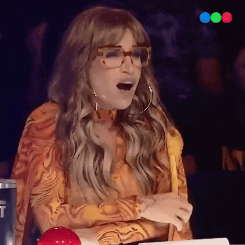 a woman wearing glasses and hoop earrings is sitting at a table