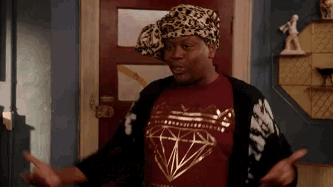 a man wearing a leopard print headband and a diamond shirt is standing in front of a door .
