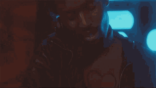 a man with a beard is standing in a dark room with blue lights