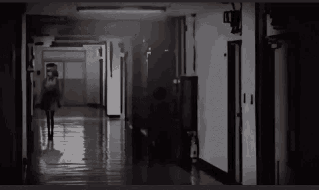 a woman in a red dress is walking down a hallway .