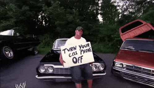 a man with a sign that says turn your cell phone off