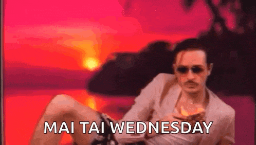 a man in a suit and sunglasses is sitting on a beach with the words mai tai wednesday written on the bottom