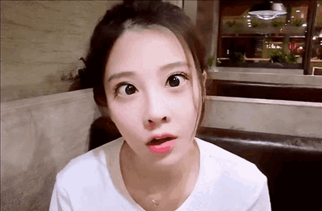 a young woman is sitting at a table in a restaurant making a funny face .