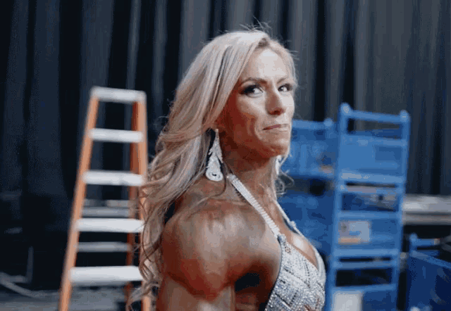 a female bodybuilder is standing in front of a ladder