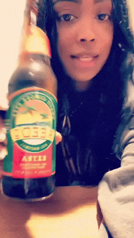 a woman is holding a bottle of beer that says artois on it