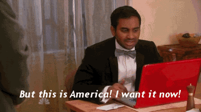 a man in a tuxedo sits at a desk with a red laptop and the words but this is america i want it now